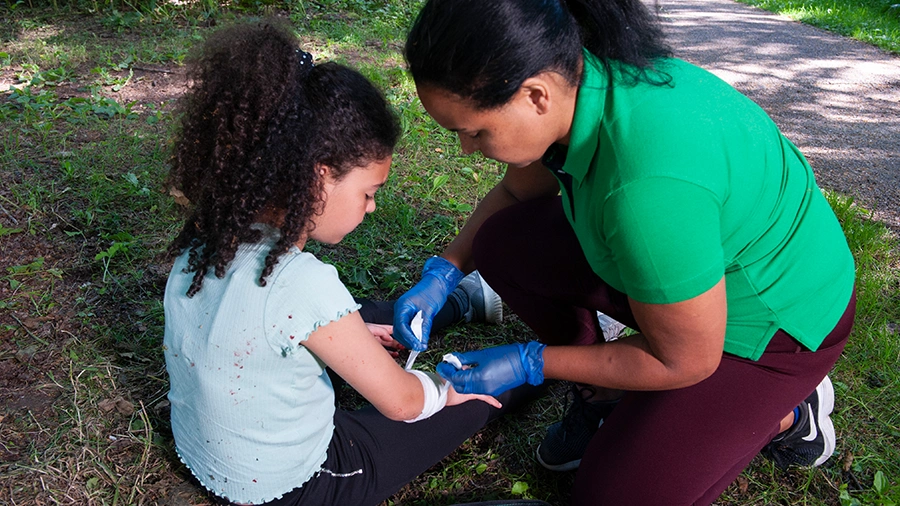 Paediatric first aider applying a bandage to a child's arm