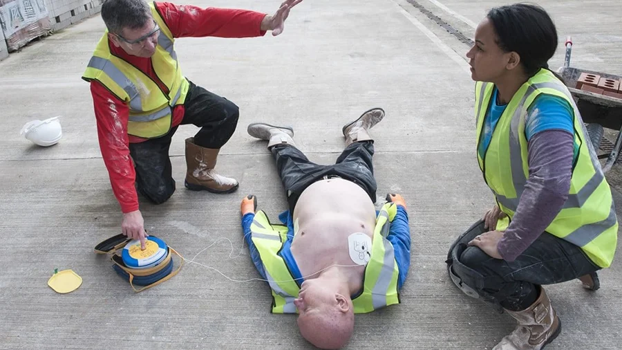 First aider using aed on a casualty