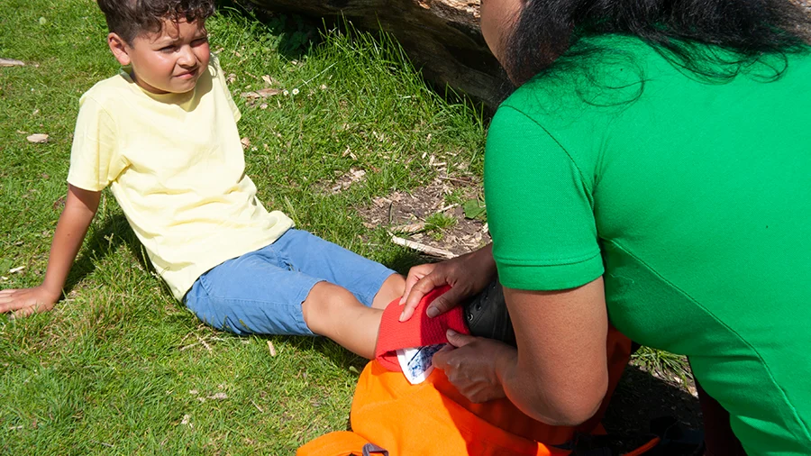 Paediatric first aider performing first aid on a child outdoors